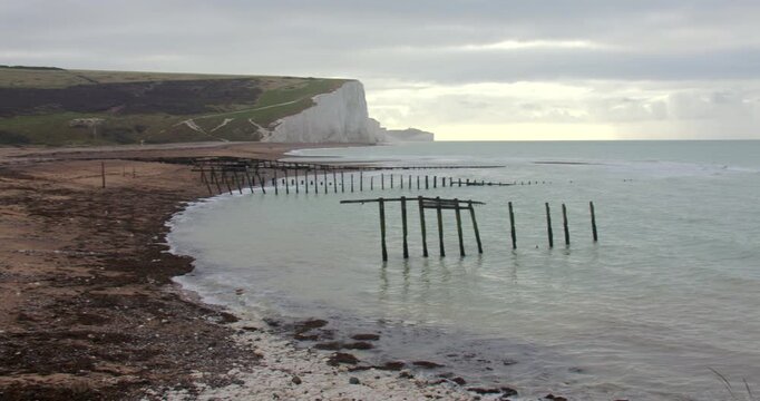 Extra Wide panning shot right to left of the Seven Sisters Cliff from the beach with broken groynes at Cuckmere haven beach next to Seaford head