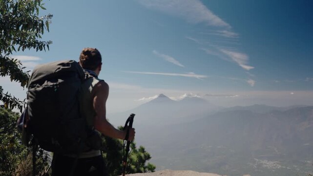 Hiker with backpack looking at Atitlan and Toliman volcanoes from Acatenango volcano