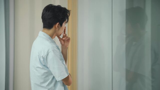 Thoughtful businessman pensive male employee standing and looking out at the rainy urban cityscape, focusing and contemplating a challenging idea or a complex problem in a professional setting