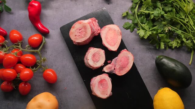 A high angle view of marrow bone slices with vegetables, herbs, and fruits on a dark gray surface a culinary journey of healthy eating