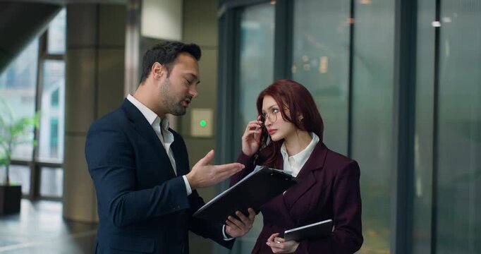 Two professionals erupt into heated argument blaming each other for project failure while shoving documents and pointing fingers in modern corporate office corridor