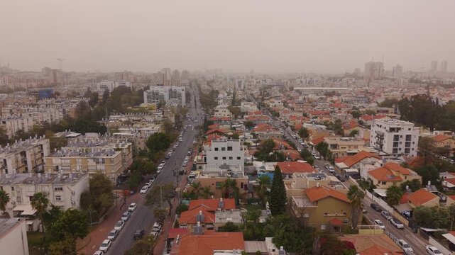 Drone footage of Jessy Cohen residential buildings in Holon obscured by heavy Israeli sandstorm with thick orange haze.