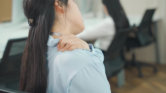 Tired businesswoman massages stiff neck, suffering from neck pain, shoulder pain from burnout, fibromyalgia muscle inflammation. Overworked female employee feels discomfort, massages rubs sore muscles