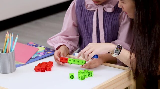 Teacher Helping Child Learn With Colorful Building Blocks