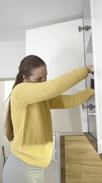 Pregnant woman using a small handheld vacuum cleaner to clean kitchen furniture. Domestic chores, spring cleaning, home maintenance, tidy interior, hygienic lifestyle, and practical household care sce