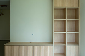 Minimalist built-in cabinet with vertical slats. Clean lines and light wood tones. Open shelves and closed storage units. Modern design fits contemporary interiors © jinhongljh