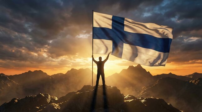 Silhouette of a person on a mountain summit holding the Finnish flag with outstretched arms against a sunset sky with visible sun rays