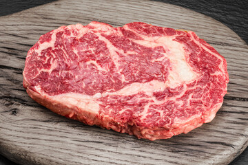 Obraz premium Raw ribeye steak on a wooden board. Top view. Macro.