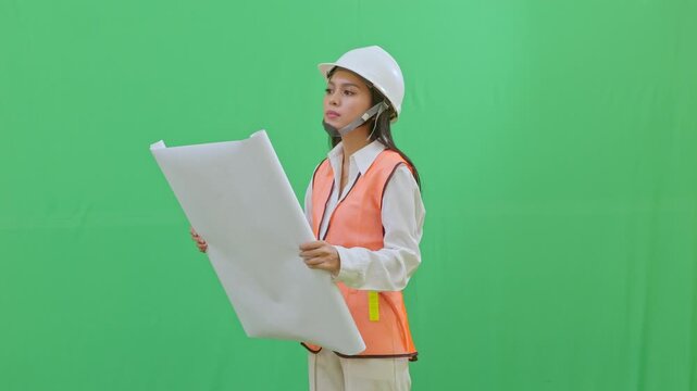 Close-up of a female engineer in a white helmet partially unrolling blueprints to quickly check technical data. Sharp and focused inspection shot on green screen.
