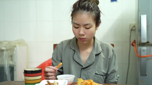 Young Asian woman eating food at home