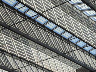Obraz premium Abstract view of a glass roof supported by a steel structure, highlighting geometric patterns, transparency, and modern architectural design.