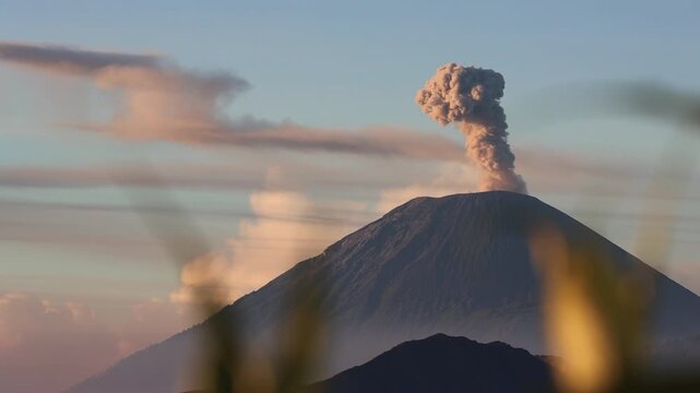 Wide shot of Sunrise Eruption of Mount Semeru Framed by Foreground Silhouettes from King Kong Hill in East Java , Indonesia