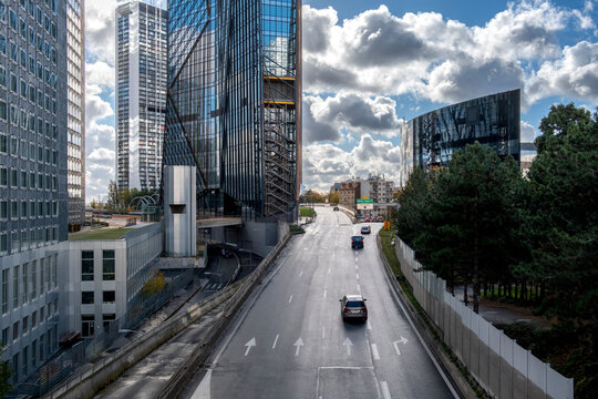 Traffic on multilane highway between towers in La Defense Paris France under dramatic clouds showing modern urban transport infrastructure and city perspective
