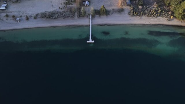Top down drone view of wooden pier extending into Lago Espejo with clear Patagonian water.