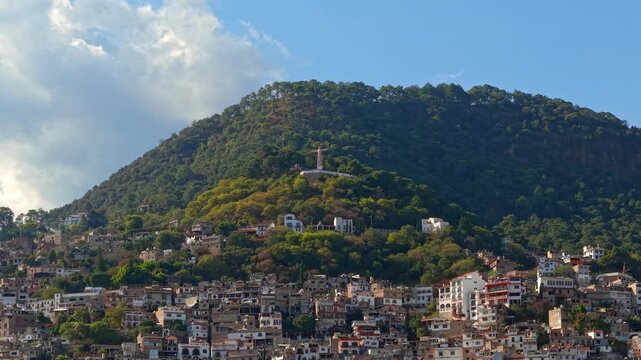 Panoramic aerial view dolly in establishing shot of Atachi Hill with residential houses on its slopes and the monumental Christ statue in Taxco, Guerrero, Mexico
