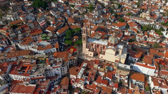 Aerial orbit establishing shot of the Santa Prisca temple in the city of Alarcon, Guerrero, Mexico, with colonial architecture and giant Christmas flower, high frame rate.