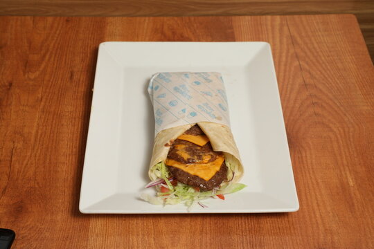 Sandwich wrap au b&oelig;uf hach&eacute;, cheddar fondant et crudit&eacute;s sur assiette blanche