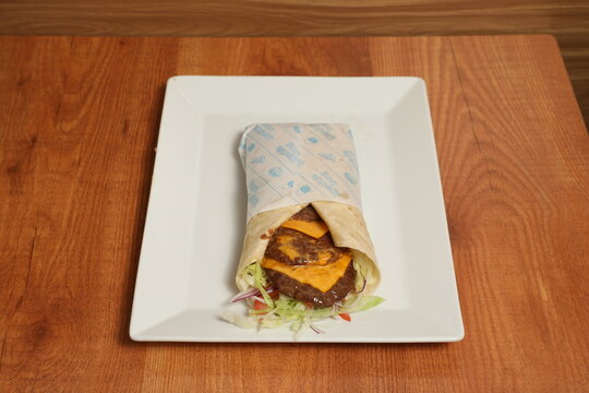 Sandwich wrap au b&oelig;uf hach&eacute;, cheddar fondant et crudit&eacute;s sur assiette blanche