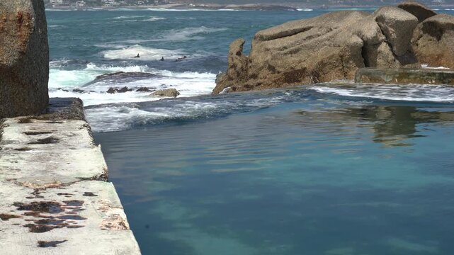 Waves crashing over the tidal pool along a rocky shoreline