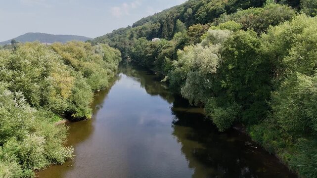 River Wye,Wye Valley, Herefordshire, slow flight from parapet of ancient stone bridge along the river with calm waters in glorious summer sunshine with forested banks and hills in the background