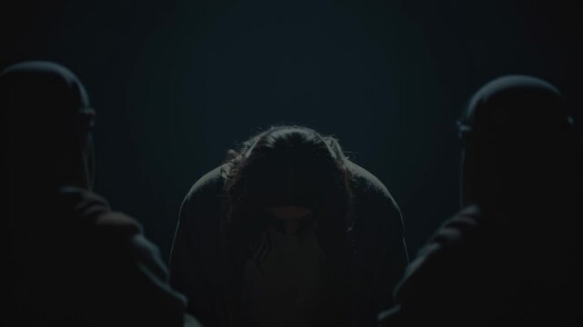 Jesus Christ surrounded by accusers in dark scene. Biblical figure bowing under judgment or condemnation. Religious concept for Good Friday and Christian Easter.