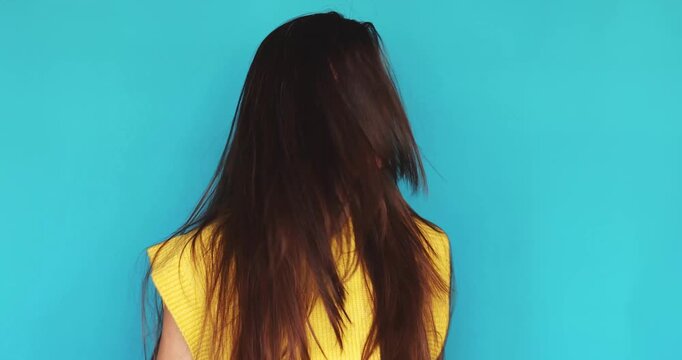 Happy young brunette woman with long hair shaking head side to side and laughing sincerely at camera, saying no with joyful expression, isolated on blue background with copy space