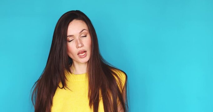 Young woman in yellow top on turquoise background asking where and pointing at wrist gesture, showing skepticism, impatience, doubt and asking for explanation about time delay with hand movements.