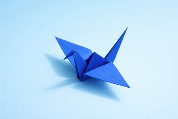 A single blue origami crane casting a shadow on a light blue background