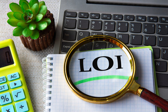 LOI acronym in notebook under magnifying glass with laptop and calculator in background