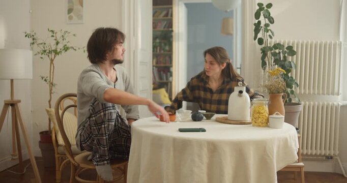 Friends enjoy a joyful moment together, sipping coffee and engaged in playful conversation in a sunny, inviting space