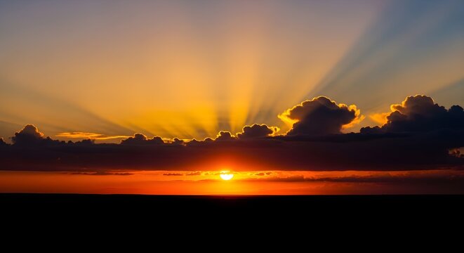 Elegant sunset display with radiant golden sun rays breaking through dramatic dark clouds over a tranquil horizon, a breathtaking natural spectacle of light