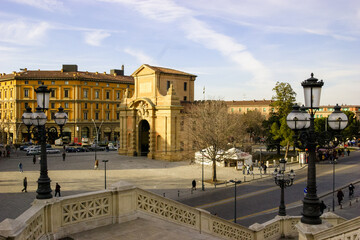 Obraz premium A view of the Porta San Giorgio in Ferrara, Italy, on a sunny day with people walking and cars driving.