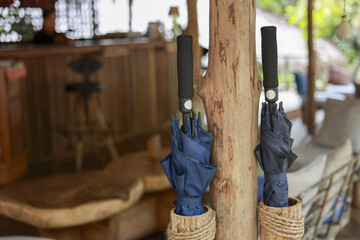 Fototapeta premium Two blue umbrellas waiting in rustic woven holder inside wooden resort lobby. calm and prepared atmosphere, ready for rainy day or tropical weather