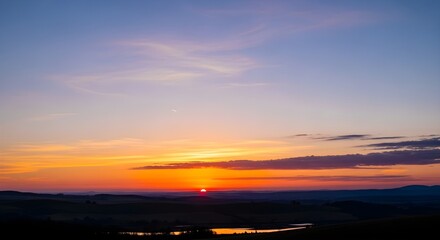 Obraz premium Serene sunset painting the horizon with vibrant hues of orange and purple, casting a peaceful glow over the natural landscape
