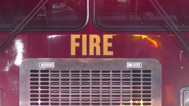 Fire truck grille with orange lettering spelling FIRE and flashing lights behind