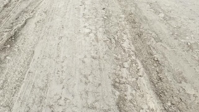 Close-up of a bumpy unpaved dirt road with deep tire tracks