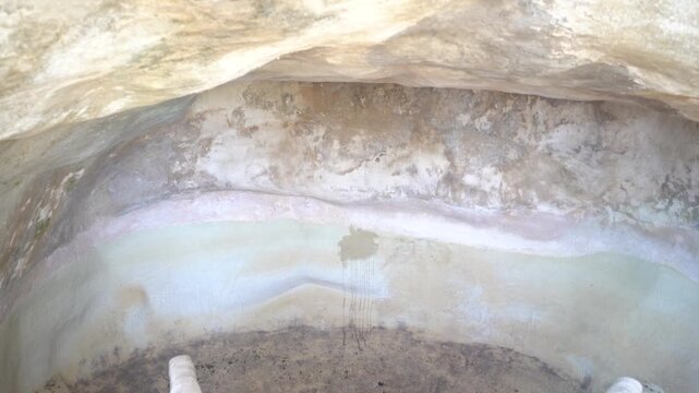 Inside hollowed rock formation showing layered mineral deposits and water stains