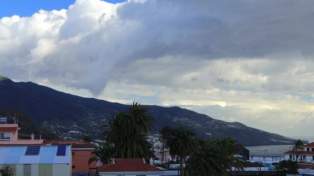 Espectacular avance acelerado de nubes densas sobre las laderas habitadas y palmeras de La Palma, debido a la tormenta Theresa mostrando el cambio atmosf&eacute;rico y la luz sobre el relieve canario.