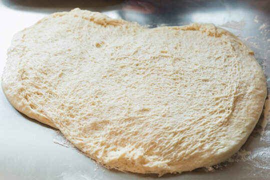 Freshly proofed bread dough with airy texture spread on a floured surface, ready for baking.