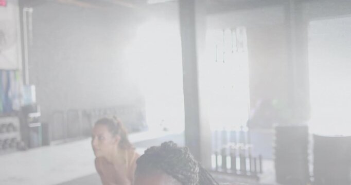 Lead woman initiating kettlebell reps for fitness training, performing upright rows, camera closing