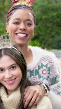 Vertical video: Walking behind woman touching seated woman wearing knits posing in yard, headbands