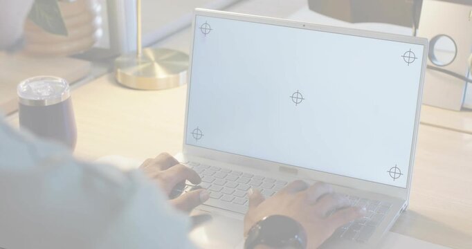 Man typing on laptop at desk, testing crosshair registration and layout alignment for tech design