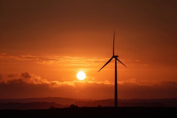 Obraz premium Wind turbine silhouette against vibrant orange sunset sky