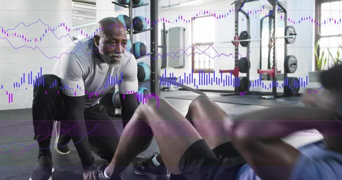 Gym trainer holding feet, cueing, trainee doing sit-ups on mat as waveform graph tracking reps