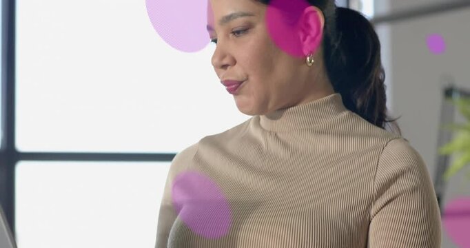 Woman typing on laptop and causing pink purple circles floating across face while demoing tech