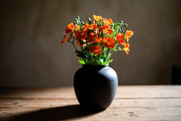 Obraz premium A small vase of orange flowers rests on a wooden table.