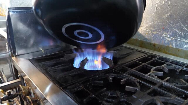 A chef melts butter in a black pan over a gas flame. The butter sizzles, bubbles and foams as it transforms into a rich, golden cooking base.