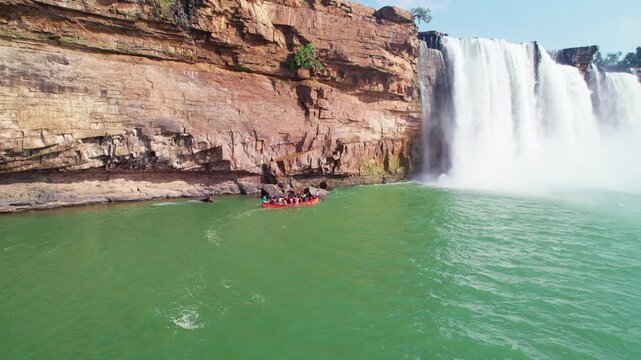 Chitrakote Waterfall drone shot with boat ride and rainbow over green water.