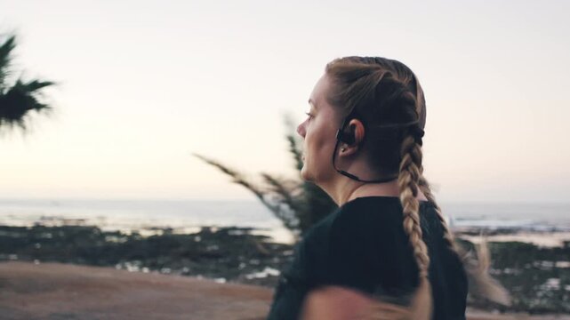 Woman, fitness and running with earphones for sprint, weightloss or outdoor workout on ocean coast. Active, female person or runner with race or exercise for cardio training, health or wellness