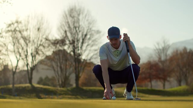 Golfer crouching low to read the line of a putt on the green in Sion, Switzerland. Focused pre-shot routine, calm golf course atmosphere, and cinematic sports preparation moment.